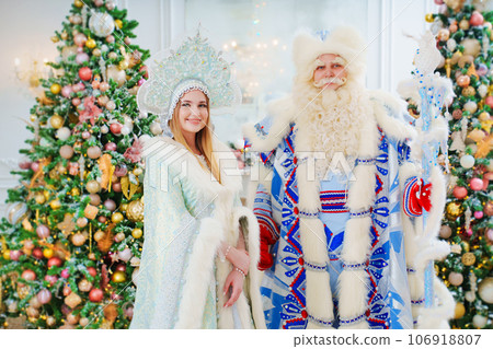 a Father Frost and Snow Maiden in blue costume in the room with christmas trees  106918807