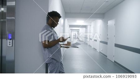 Doctor stands in hospital corridor leaning wall Doctor stands in hospital corridor leaning wall 106919093