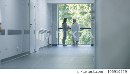 Nurse comes to elderly female patient in clinic corridor Nurse comes to elderly female patient in clinic corridor 106919259