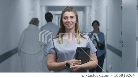 Female doctor stands in modern clinic corridor, looks at camera 106919264