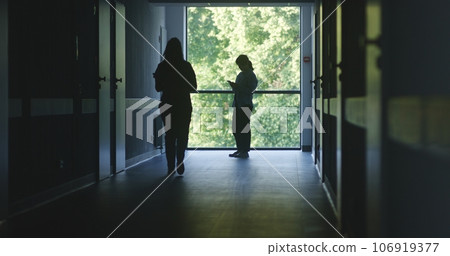 Medical staff and patients walk in dark clinic corridor Medical staff and patients walk in dark clinic corridor 106919377