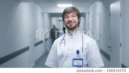 Male nurse, doctor stands in clinic corridor, looks at camera 106919378