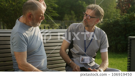 Doctor sits with patient and examines his shoulder Doctor sits with patient and examines his shoulder 106919450