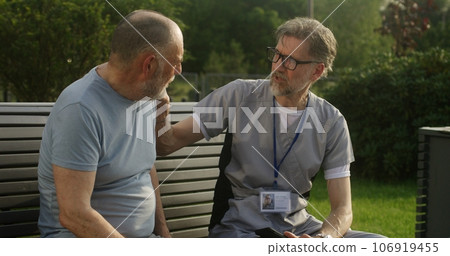 Doctor sits with patient and examines his shoulder 106919455
