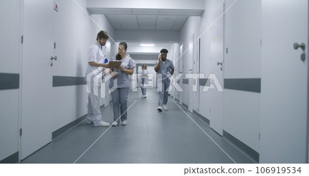 Multiracial medical staff walk clinic corridor 106919534