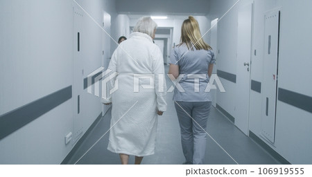 Nurse helps elderly woman to get to hospital ward 106919555