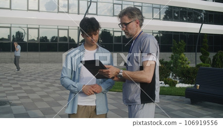 Doctor stands with adult patient at entrance Doctor stands with adult patient at entrance 106919556