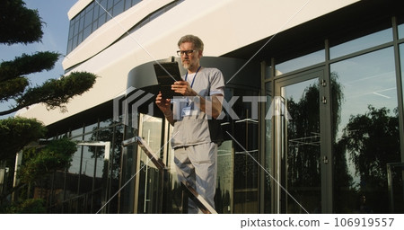 Mature doctor uses tablet computer, checks medical tests results Mature doctor uses tablet computer, checks medical tests results 106919557