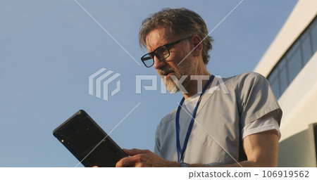 Doctor talks, consults patient online by video call using digital tablet 106919562