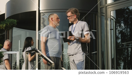Physician stands with patient at clinic entrance Physician stands with patient at clinic entrance 106919563