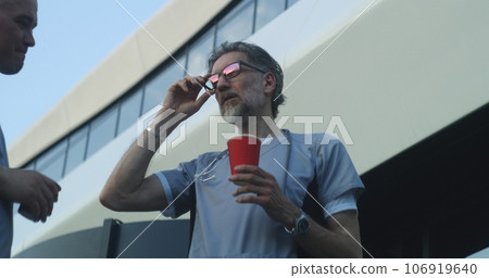 Mature medic drinks coffee, discusses work with colleague Mature medic drinks coffee, discusses work with colleague 106919640