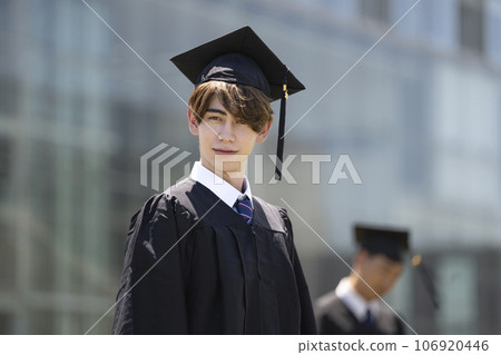 Graduation ceremony image of a male student looking at the camera wearing an academic gown Graduation ceremony image of a male student looking at the camera wearing an academic gown 106920446