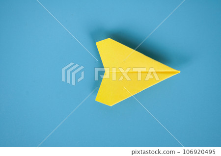 Top view of yellow paper airplane on blue background. Space for text or ideas. Top view of yellow paper airplane on blue background. Space for text or ideas. 106920495