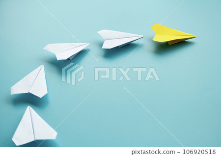 Top view of yellow paper airplane origami leading other white paper airplanes with customizable space for text 106920518