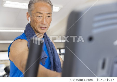 A middle-aged man setting up an exercise bike at a sports gym 106921947