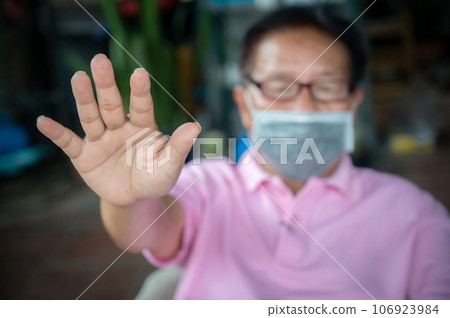 Senior man wearing mask and show stop hand gesture for social distancing. Social distancing is the physical space between people to avoid spreading illness. Senior man wearing mask and show stop hand gesture for social distancing. Social distancing is the physical space between people to avoid spreading illness. 106923984