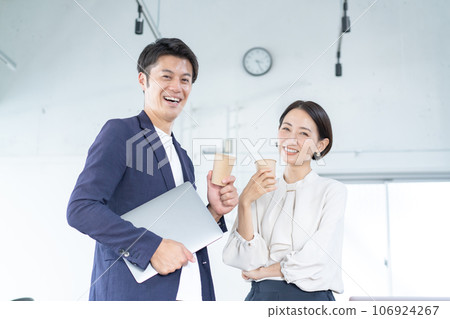 A man and a woman chatting with colleagues in the office 106924267