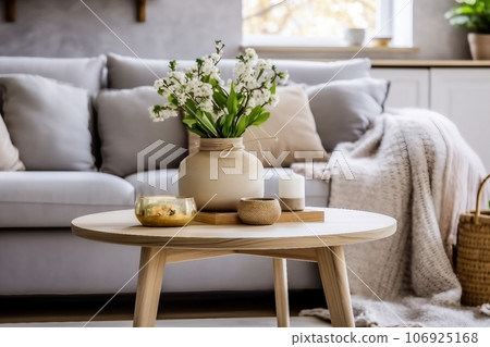 Scandinavian living room interior with design grey sofa, wooden coffee table, plants, shelf, spring flowers in vase, decoration and elegant personal accessories at home decor. 106925168