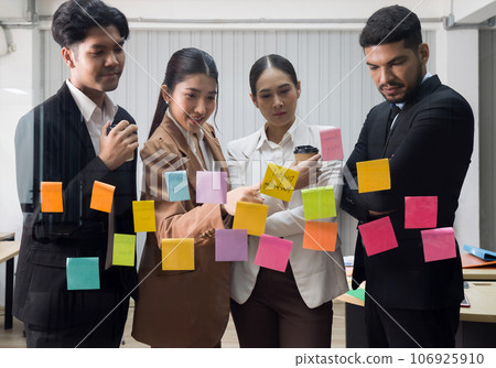 Group of business people in suit meeting with sticky paper notes on the glass wall for new ideas. Using agile methodology for business in a tech start-up office. Group of business people in suit meeting with sticky paper notes on the glass wall for new ideas. Using agile methodology for business in a tech start-up office. 106925910