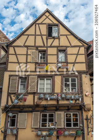 Facade of a traditional Alsatian house decorated with old watering cans in the city center. 106927464
