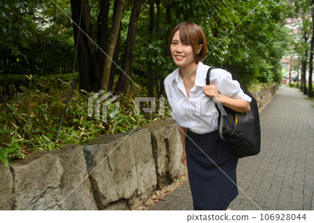 A woman walking on the sidewalk after the rain 106928044