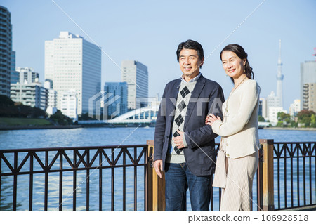 A middle-aged couple having a date by the river in the city 106928518