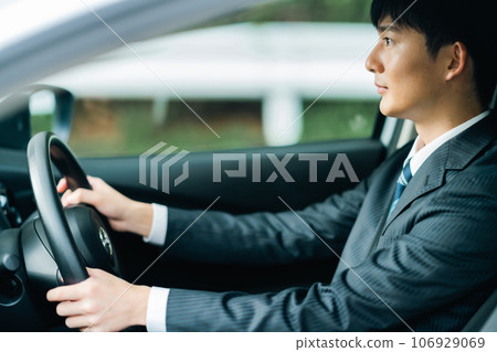A man in a suit driving a gray regular car 106929069