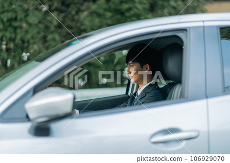一個穿著西裝的男人駕駛著一輛灰色普通車 106929070