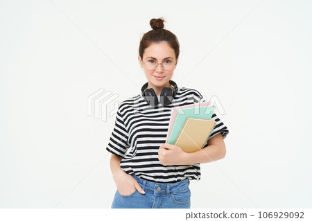 Student lifestyle and people concept. Portrait of young woman in glasses, teacher or college girl with books and study material, posing over white background 106929092