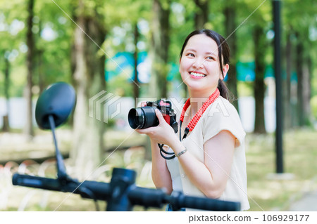 一名女子在電動滑板上旅行時用相機拍照 106929177