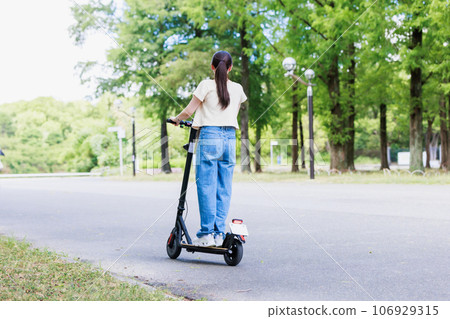 A young woman running refreshingly on an electric kickboard 106929315