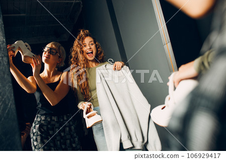 Beautiful young woman stylist designer helping choose clothes to customer client at mirror. Shopping Black Friday concept 106929417