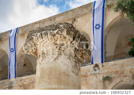Ancient capital of a column close up with long israeli flags on the background Ancient capital of a column close up with long israeli flags on the background 106932327