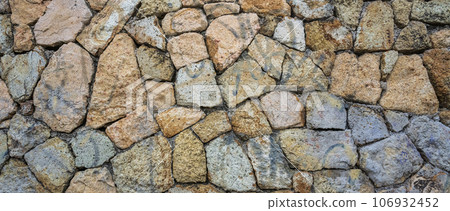 Fragment of a natural stone wall as a background or texture. The structure of the stone wall. Old castle stone wall texture background. 106932452