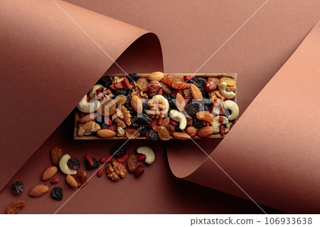 The mix of dried fruits and berries on a brown background. The mix of dried fruits and berries on a brown background. 106933638