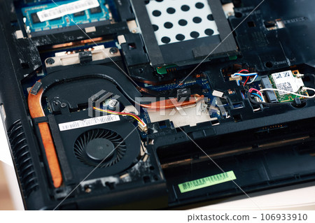 Fixing laptop. Repairman holds cooling fan and repairs from overheating. Disassembling computer, replacement, clean dust and dirt cooling system on notebook. Professional electronic device service 106933910