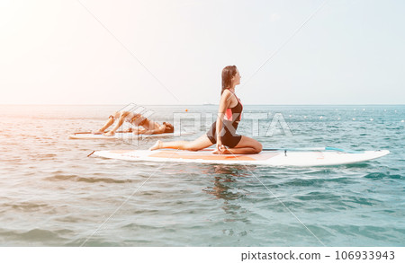 Woman man sup yoga. Happy young sporty couple practising yoga pilates on paddle sup surfboard. Female stretching doing workout on sea water. Modern family outdoor summer sport activity. Woman man sup yoga. Happy young sporty couple practising yoga pilates on paddle sup surfboard. Female stretching doing workout on sea water. Modern family outdoor summer sport activity. 106933943