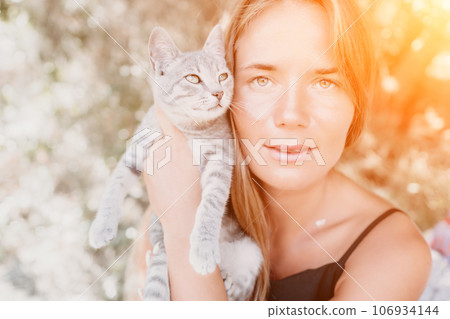 Woman summer travel cat. A woman on vacation with her pet cat enjoying a photo session on the beach. Travel and holiday concept. 106934144