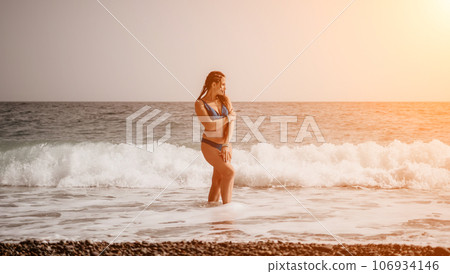 A tourist woman in blue bikini on beach enjoys the turquoise sea during her summer holiday. Rear view. Beach vacation. woman with braids dreadlocks standing with her arms raised enjoying beach ocean. A tourist woman in blue bikini on beach enjoys the turquoise sea during her summer holiday. Rear view. Beach vacation. woman with braids dreadlocks standing with her arms raised enjoying beach ocean. 106934146
