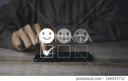 Businessman choosing happy smiley face icon to give satisfaction in service. Businessman choosing happy smiley face icon to give satisfaction in service. 106935712