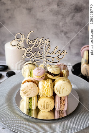 Macaroons in the form of a cake with a candle on a gray background. Happy Birthday. Macaroons in the form of a cake with a candle on a gray background. Happy Birthday. 106936779