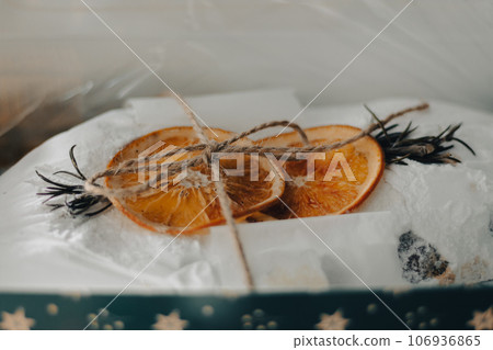 Christmas stollen decorated with dried orange fruits and spruce branch. New Year holiday baking. Sweet present. Wrapped traditional Christmas cake. December celebration. Homemade stollen. Christmas stollen decorated with dried orange fruits and spruce branch. New Year holiday baking. Sweet present. Wrapped traditional Christmas cake. December celebration. Homemade stollen. 106936865