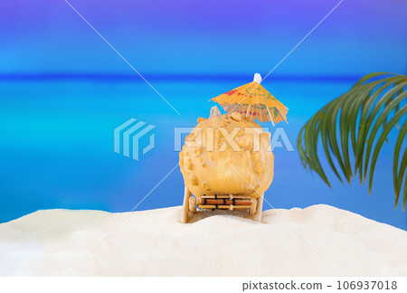 Halloween and Thanksgiving party on beach. Pumpkin on sun lounger on sand with palm tree. Autumn season on background of ocean in hot countries. Copy space 106937018