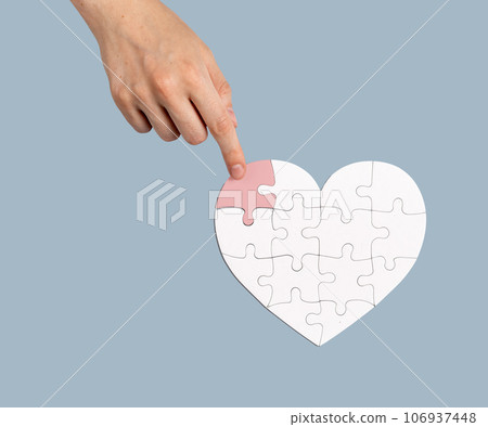 The final touch. Placing the missing puzzle piece to heart-shaped jigsaw. Help, donation concept 106937448