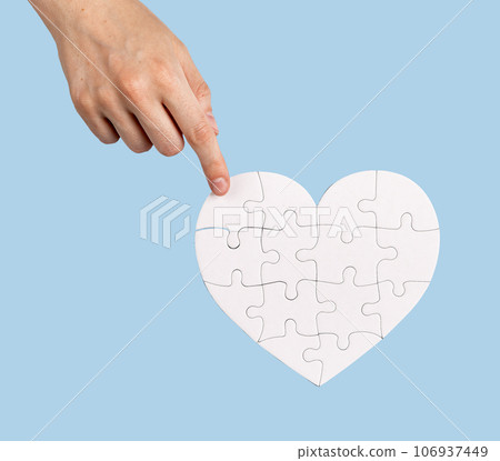 The final touch. Placing the missing puzzle piece to heart-shaped jigsaw 106937449
