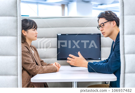 Businessmen and businesswomen talking at private booths Businessmen and businesswomen talking at private booths 106937482