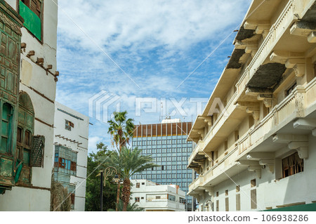 Al-Balad old town street with traditional muslim houses and modern building in the background, Jeddah, Saudi Arabia Al-Balad old town street with traditional muslim houses and modern building in the background, Jeddah, Saudi Arabia 106938286