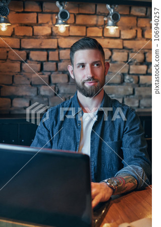 Handsome young man working on laptop while enjoying coffee in cafe Handsome young man working on laptop while enjoying coffee in cafe 106940257