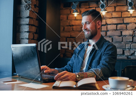 Handsome young man working on laptop while enjoying coffee in cafe 106940261