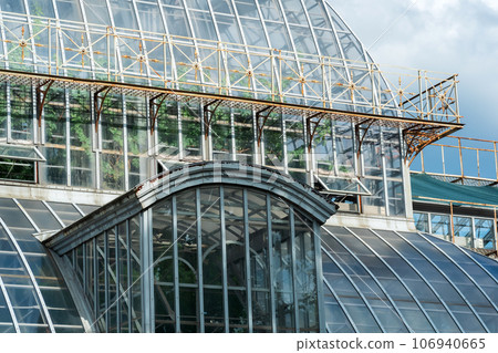 view of the glass walls and domes of a large vintage palm greenhouse 106940665